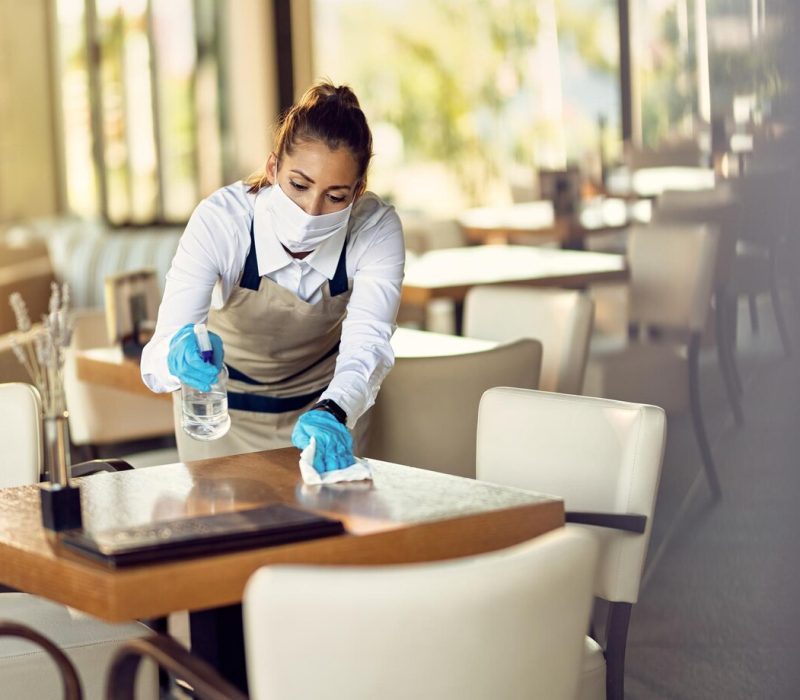 waitress-with-face-mask-disinfecting-restaurant-tables-due-to-coronavirus-pandemic_637285-11368